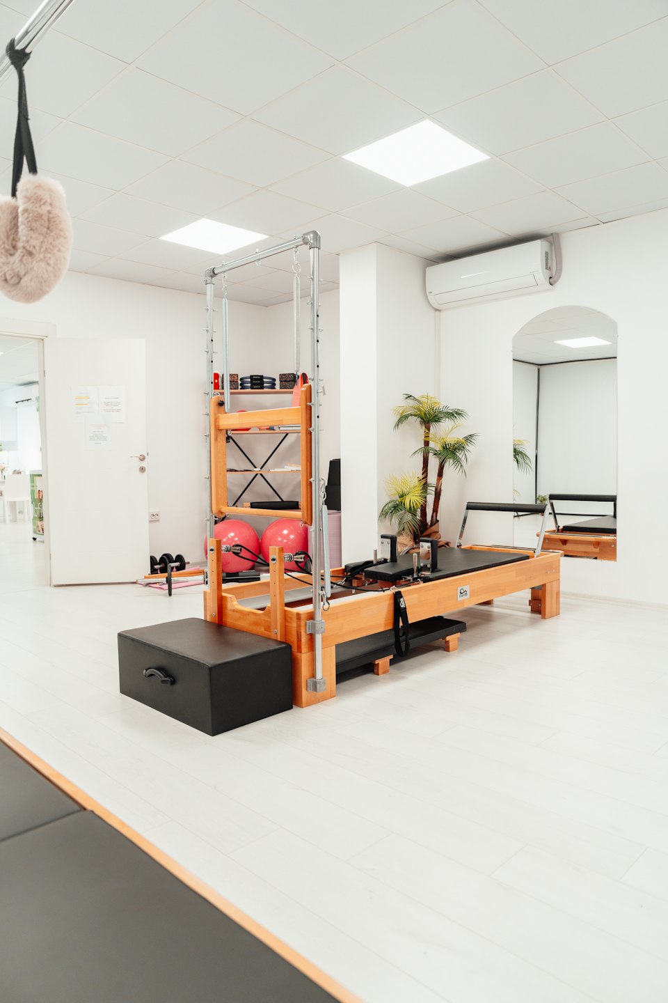 Aparat do pilatesu stoi w jasnym studiu ćwiczeń.