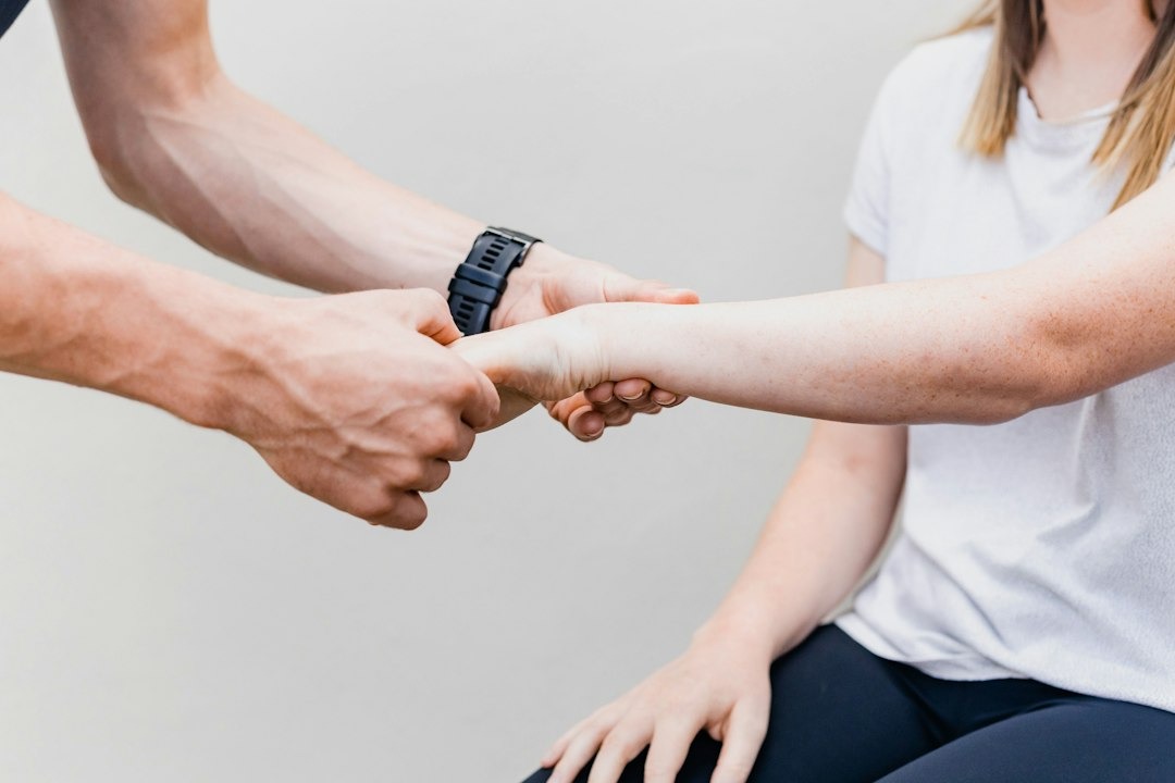 Physiotherapist examines patient's forearm and wrist.
