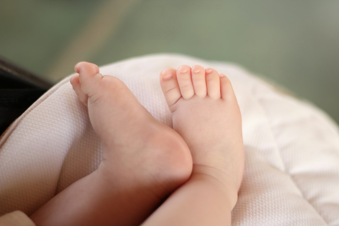 Tiny infant feet resting on a quilted white surface.